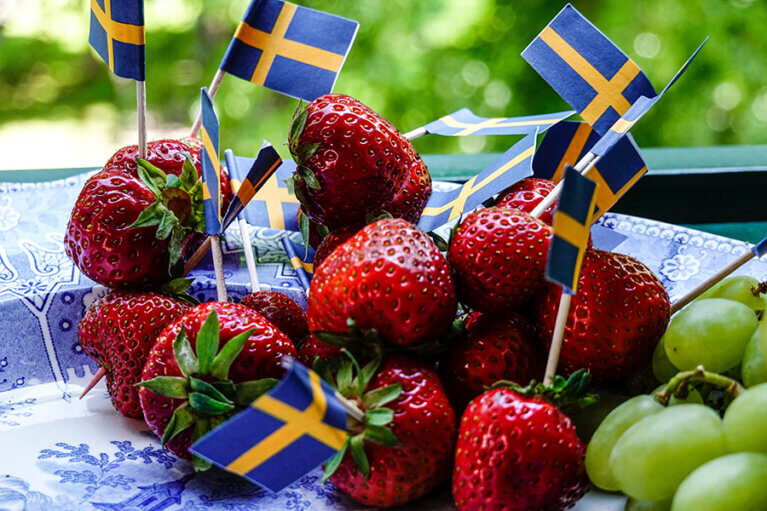 Jordgubbar och små Sverigeflaggor på ett fat.