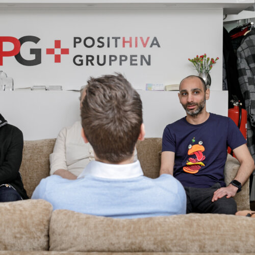 En grupp män i olika åldrar samtalar i Posithiva Gruppens lokal.