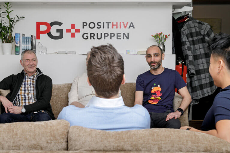 En grupp män i olika åldrar samtalar i Posithiva Gruppens lokal.