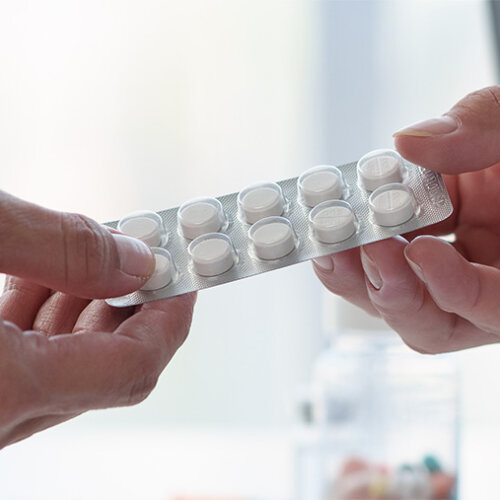 En hand överräcker en tablettkarta till en annan persons hand.