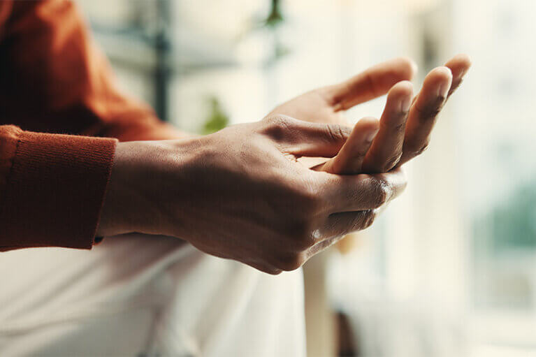 En person sitter framåtlutad och rör oroligt sina händer som i en förberedelse för att säga något.
