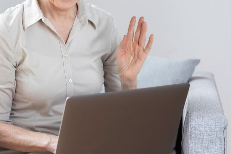 En person räcker upp handen i ett digitalt möte.