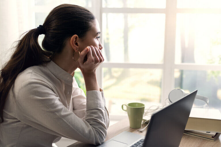 En person sitter med huvudet i handen och blickar ut genom fönstret.
