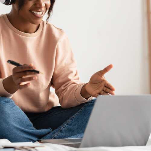 En person sitter på sin säng och pratar engagerat med någon i ett digitalt möte.