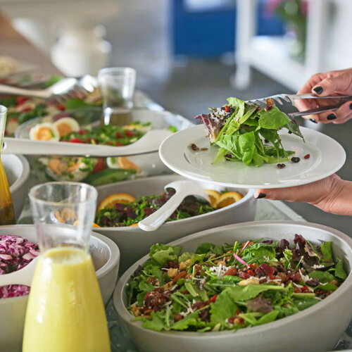 En person med nagellack tar mat från ett buffebord.